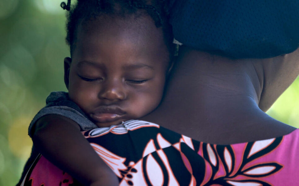 mom hugging her spleeping baby. She is tiered and so is her mother.