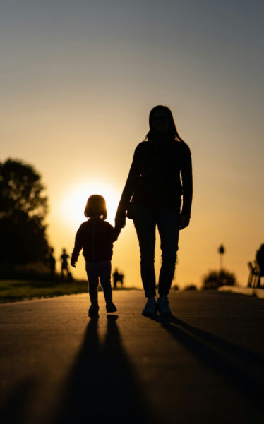 Motherhood - mom walking with kid sunset
